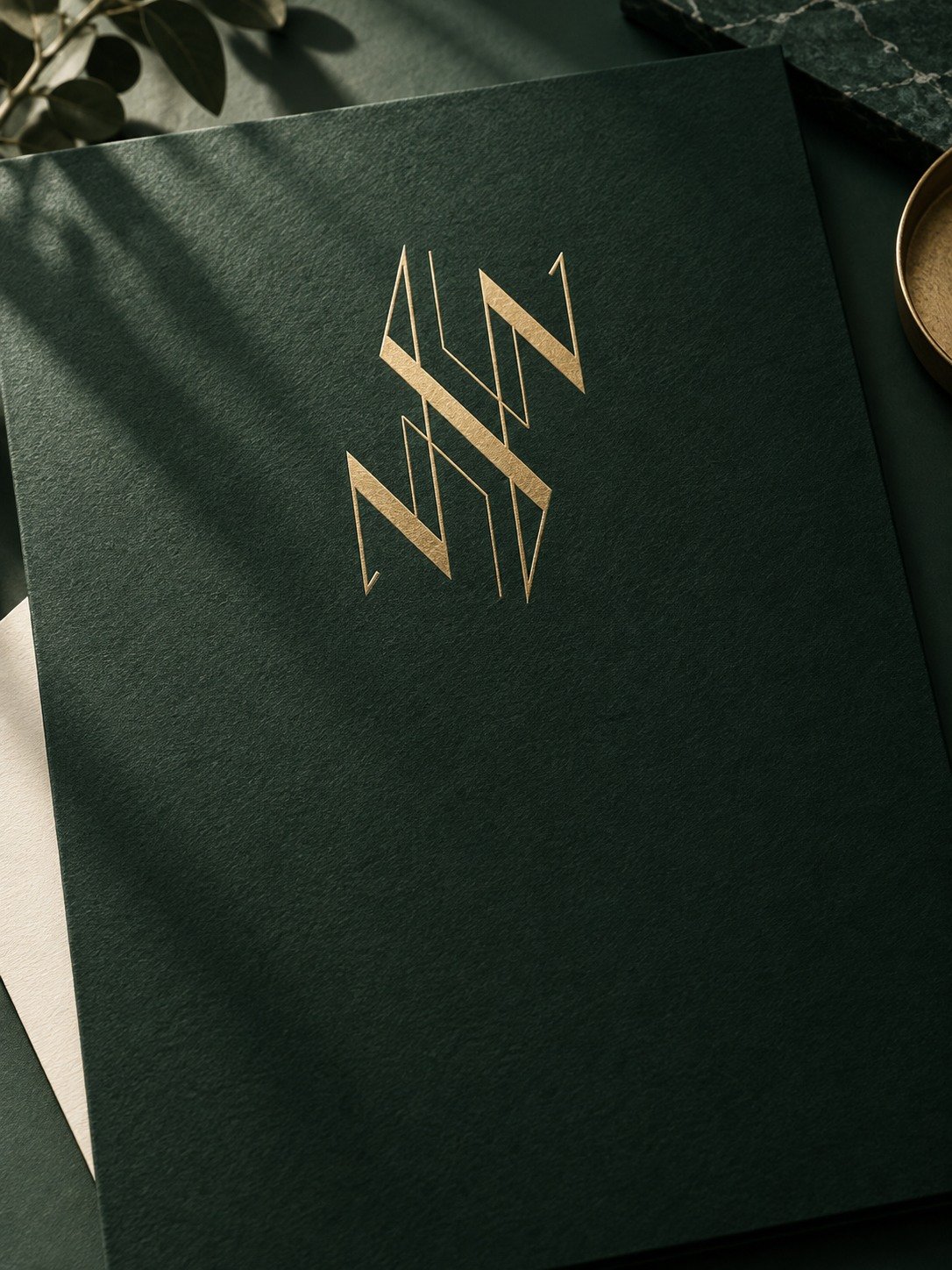 Logo NHN-Graphic Designer doré sur un papier vert profond