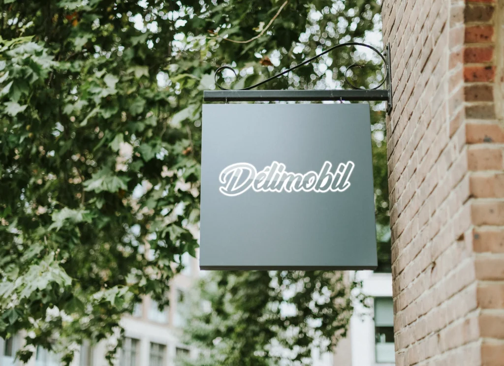 Enseigne suspendue verte portant le logotype Delimobil